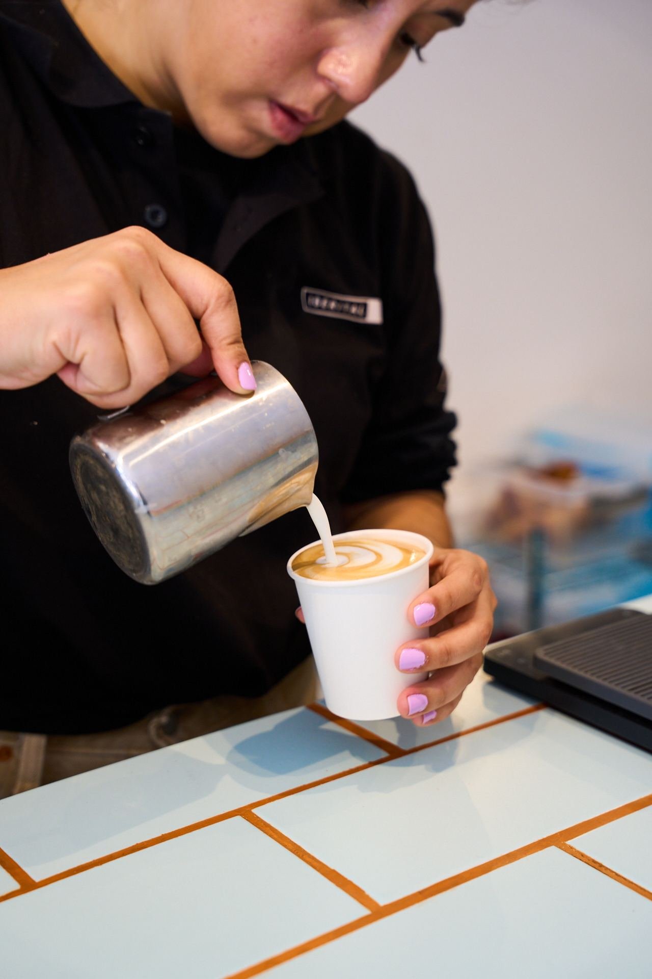 Barista haciendo latte art en un vaso para llevar