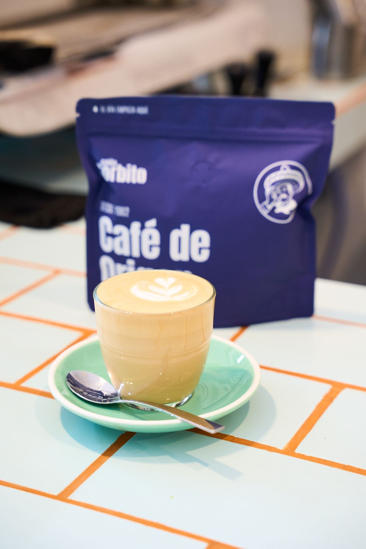 Cortado con latte art delante de una bolsa de Café de Origen de Sorbito
