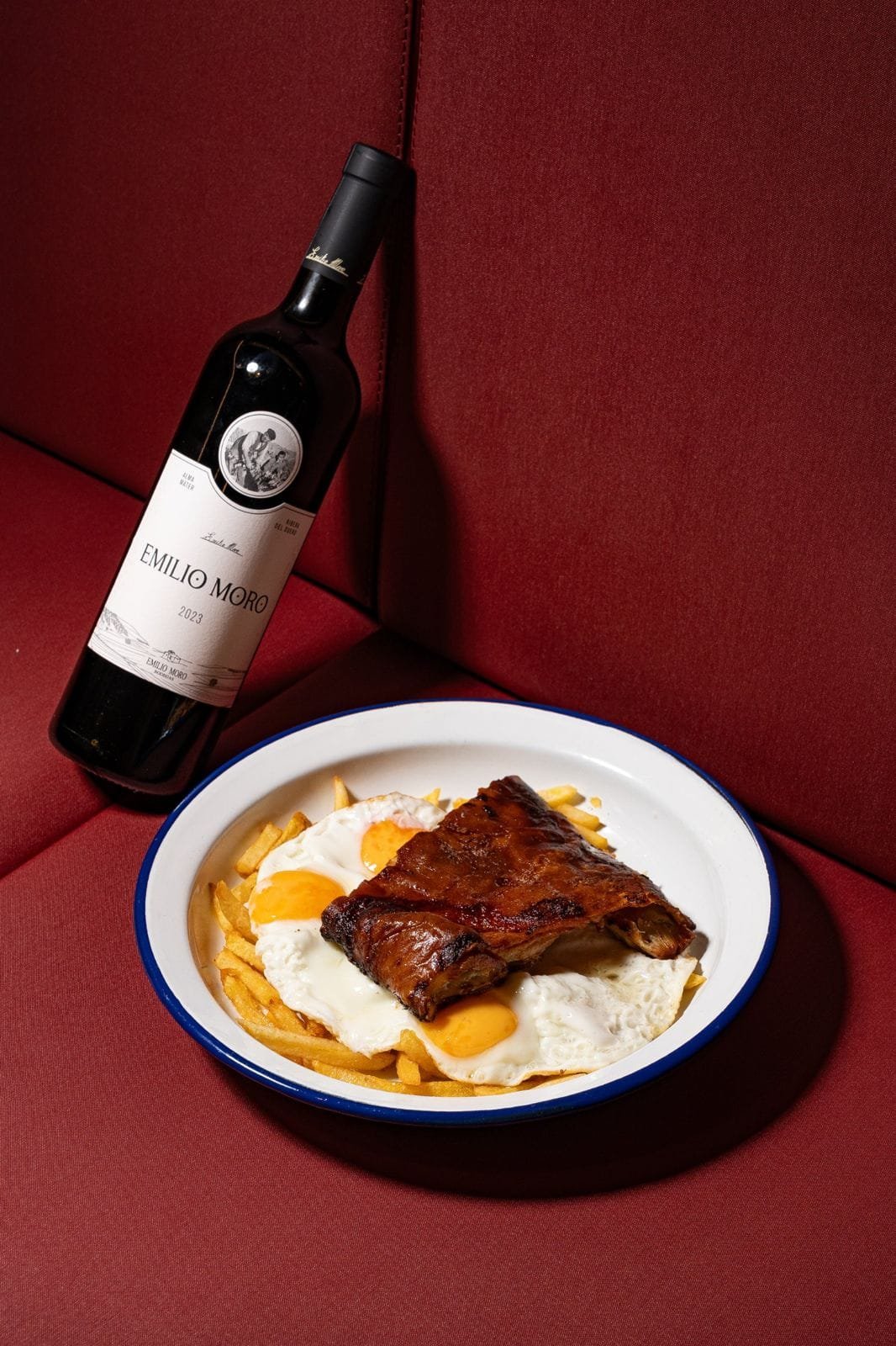 Costillas con huevos y patatas y botella de vino