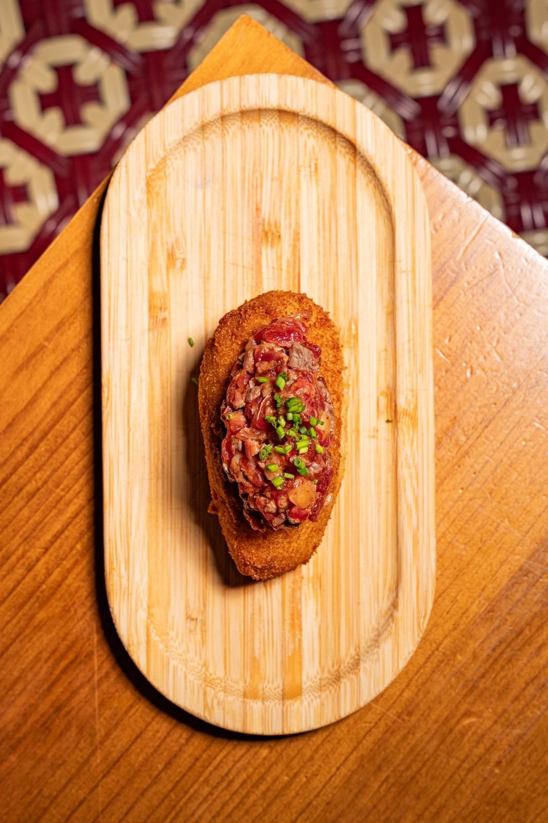 Tapa de steak tartar sobre tabla de madera