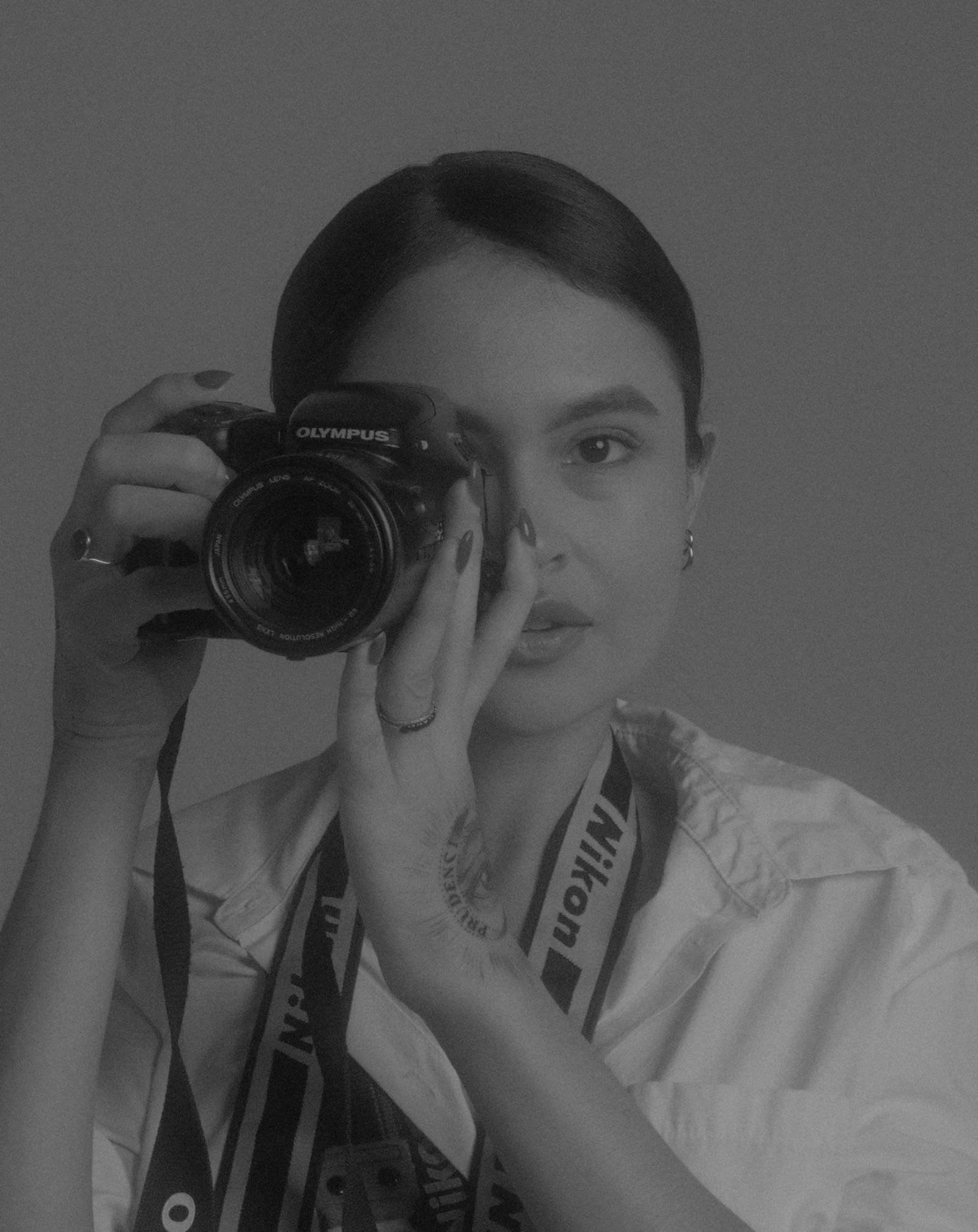Retrato en blanco y negro de una fotógrafa sosteniendo la cámara