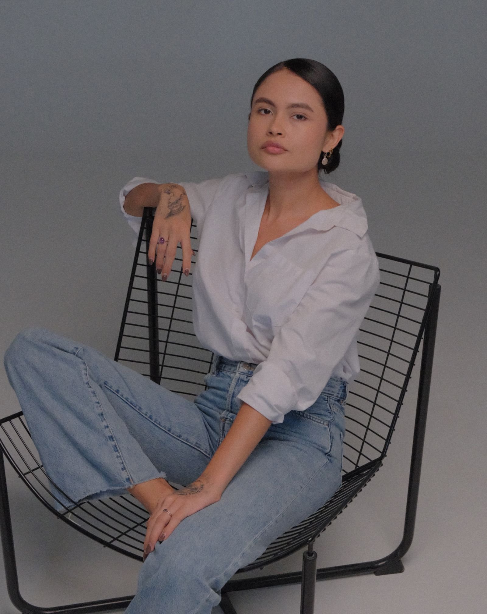 Retrato corporativo sentada en una silla de diseño sobre fondo gris