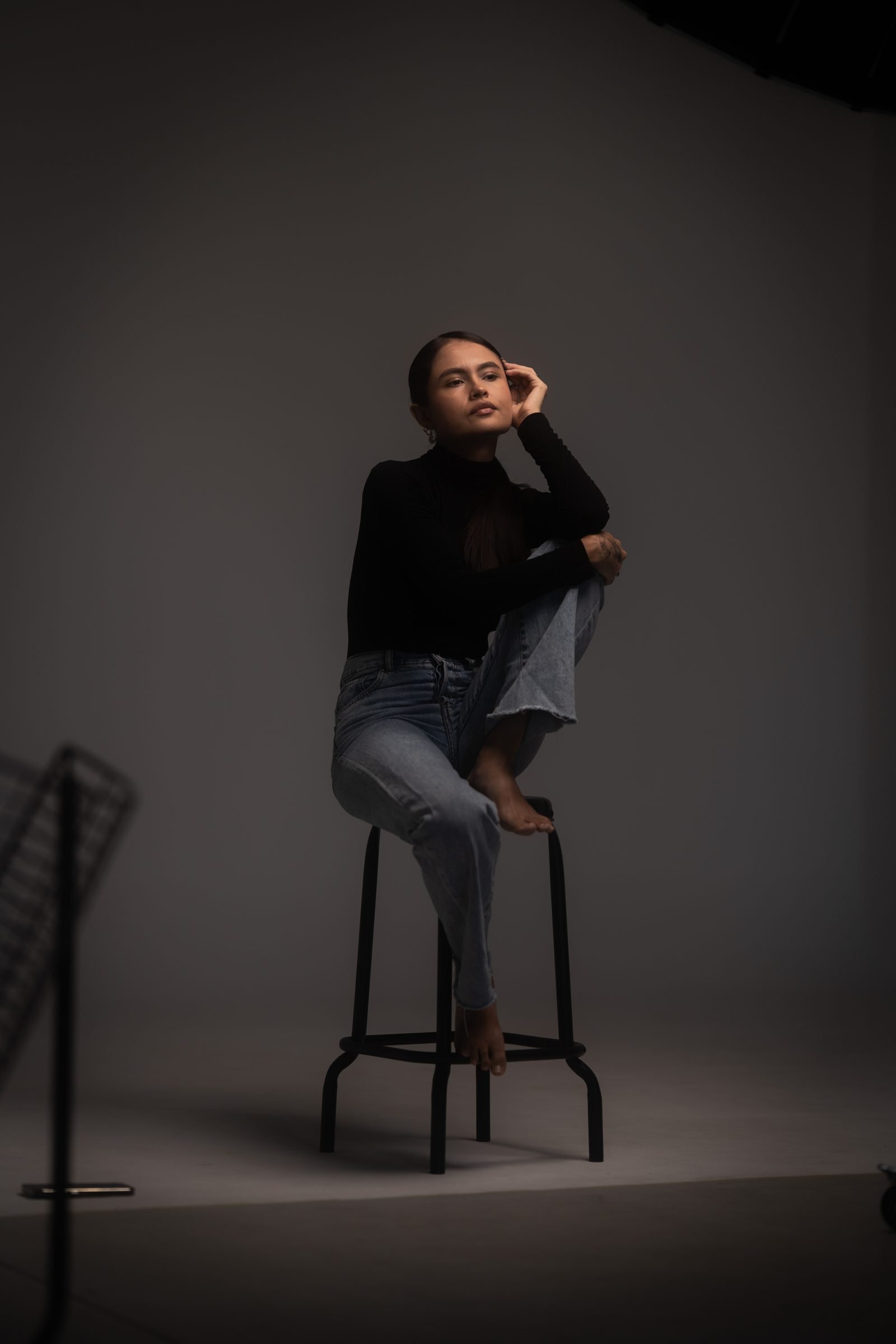 Retrato de cuerpo entero sentada en un taburete en el estudio